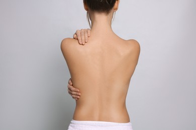 Photo of Back view of woman with perfect smooth skin on light grey background. Beauty and body care