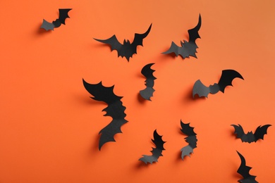 Photo of Paper bats on orange background, flat lay. Halloween decor