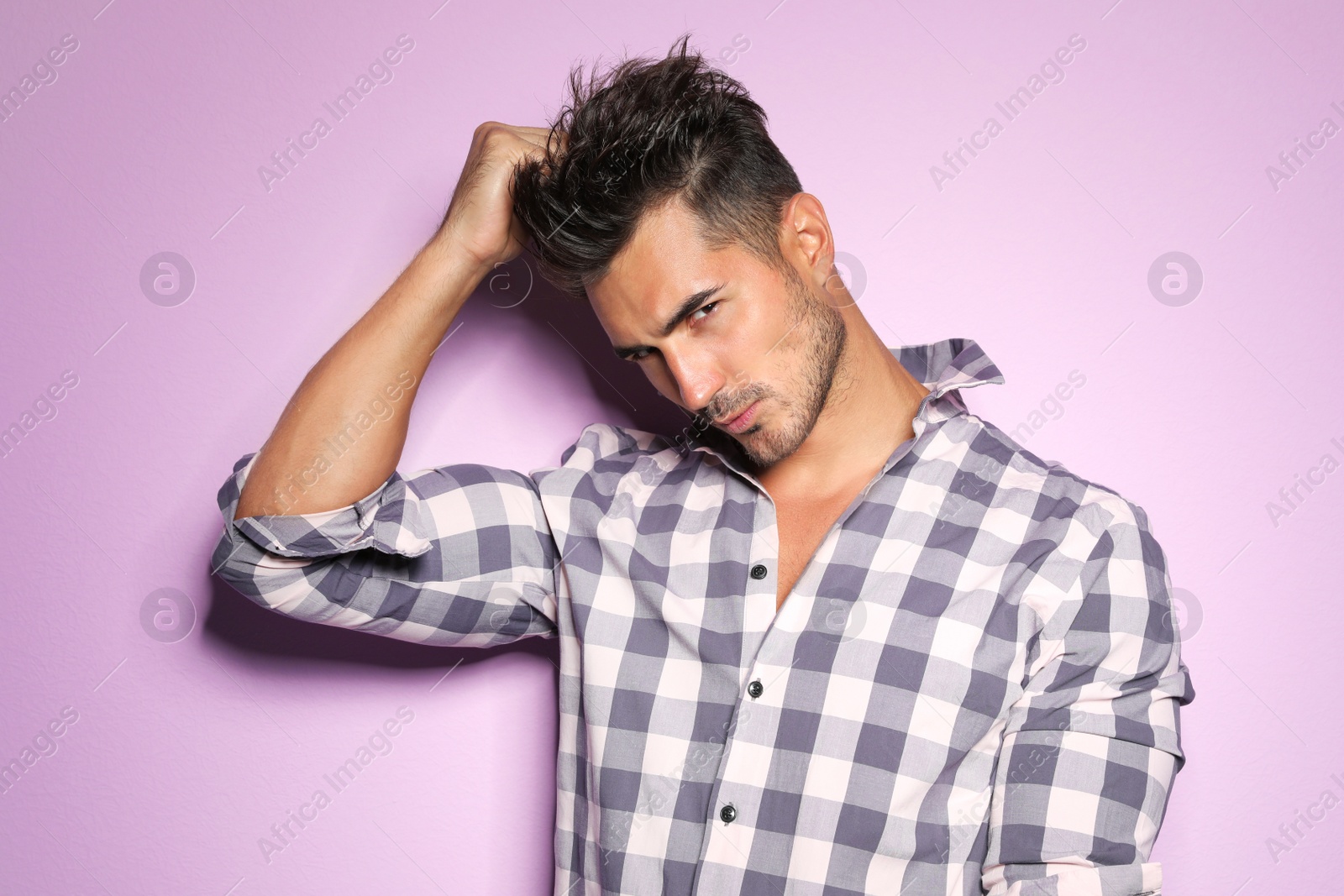 Photo of Young man with trendy hairstyle posing on color background