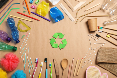 Photo of Recycling symbol and household goods on beige background, flat lay