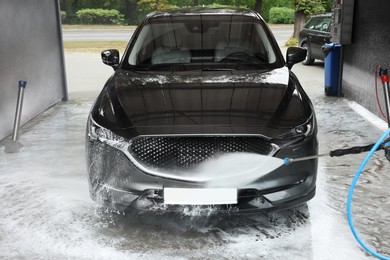 Photo of Washing auto with high pressure water jet at outdoor car wash