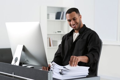 Photo of Happy man working with documents at grey table in office
