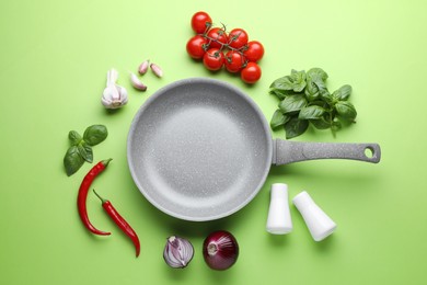 Flat lay composition with frying pan and fresh products on green background