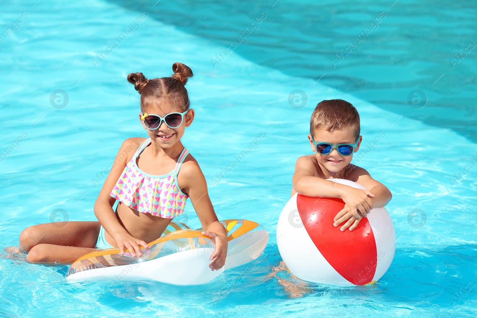 Photo of Cute little children with inflatable toys in swimming pool