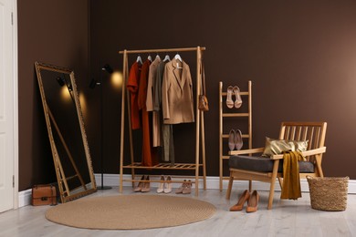 Photo of Modern dressing room interior with clothing rack, mirror and comfortable armchair