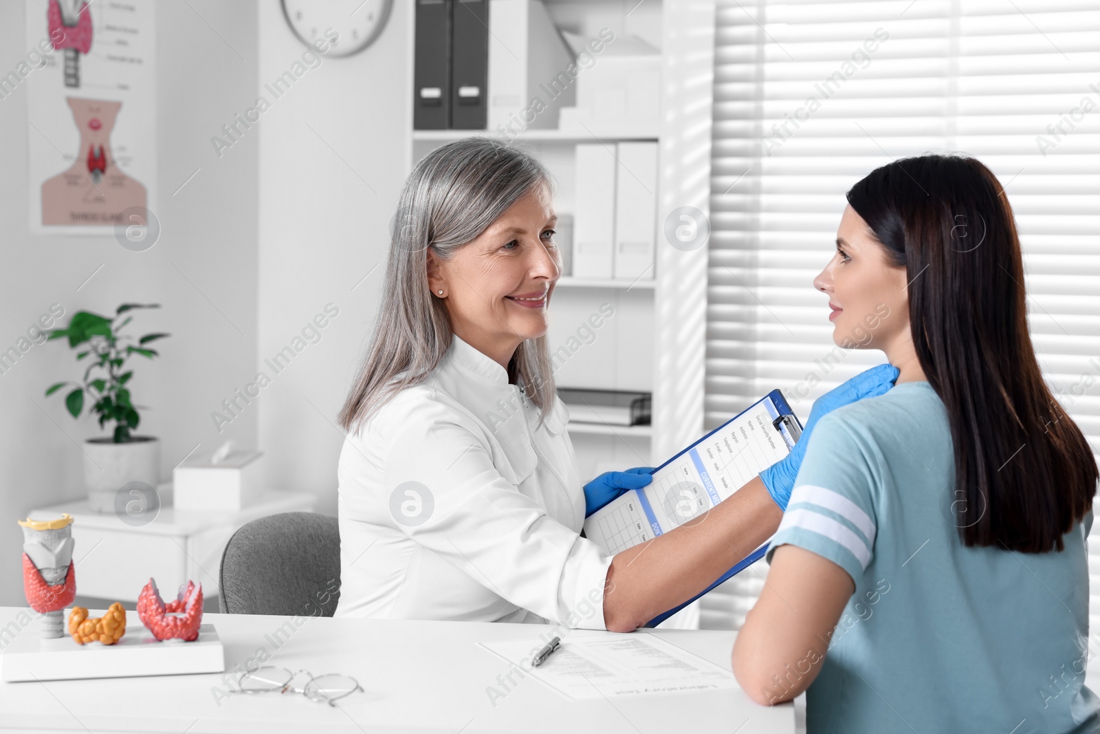 Photo of Endocrinologist examining thyroid gland of patient at table in hospital