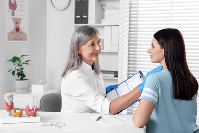 Endocrinologist examining thyroid gland of patient at table in hospital