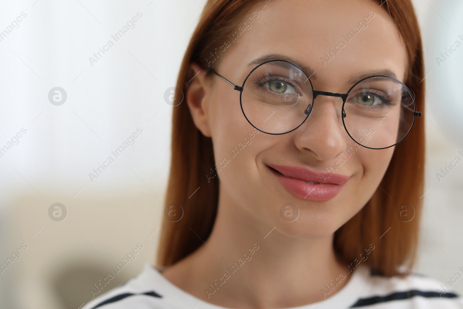 Photo of Portrait of beautiful young woman with red hair on blurred background. Attractive happy lady looking into camera. Space for text