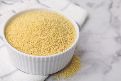 Photo of Raw couscous in bowl on light table, closeup