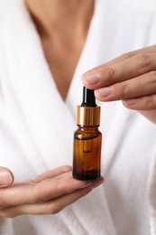 Woman with bottle of cosmetic serum, closeup