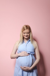 Photo of Beautiful pregnant woman in dress on color background