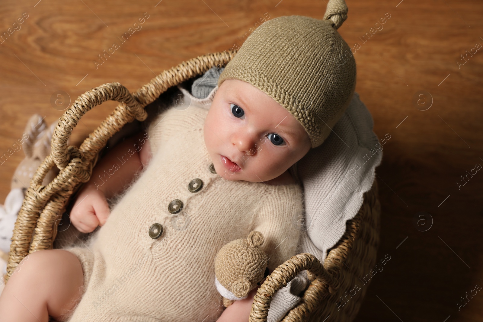 Photo of Cute little baby with knitted bear toy in wicker basket, top view