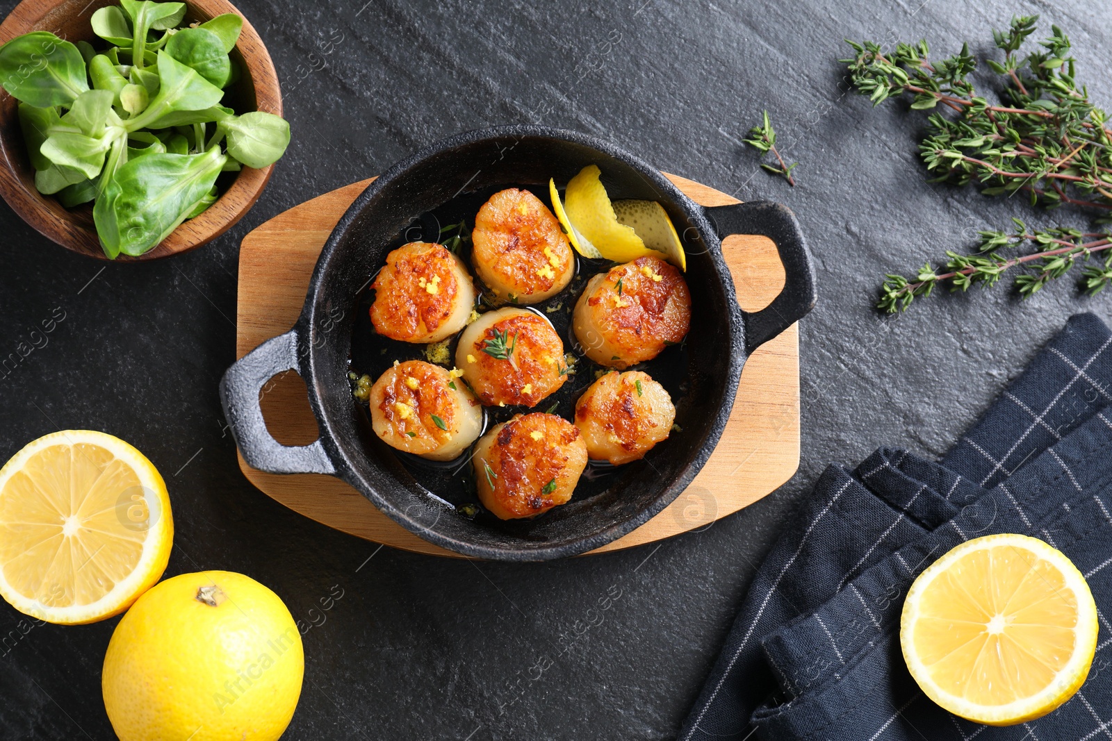 Photo of Delicious fried scallops and ingredients on dark gray textured table, flat lay