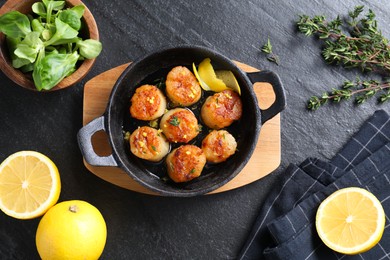 Delicious fried scallops and ingredients on dark gray textured table, flat lay