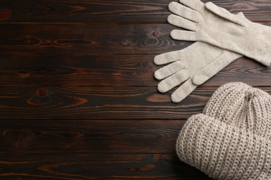Photo of Woolen gloves and hat on wooden background, flat lay. Space for text