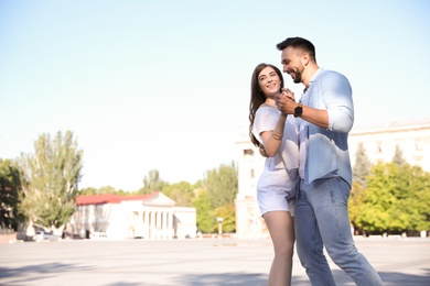 Photo of Lovely young couple dancing together outdoors on sunny day