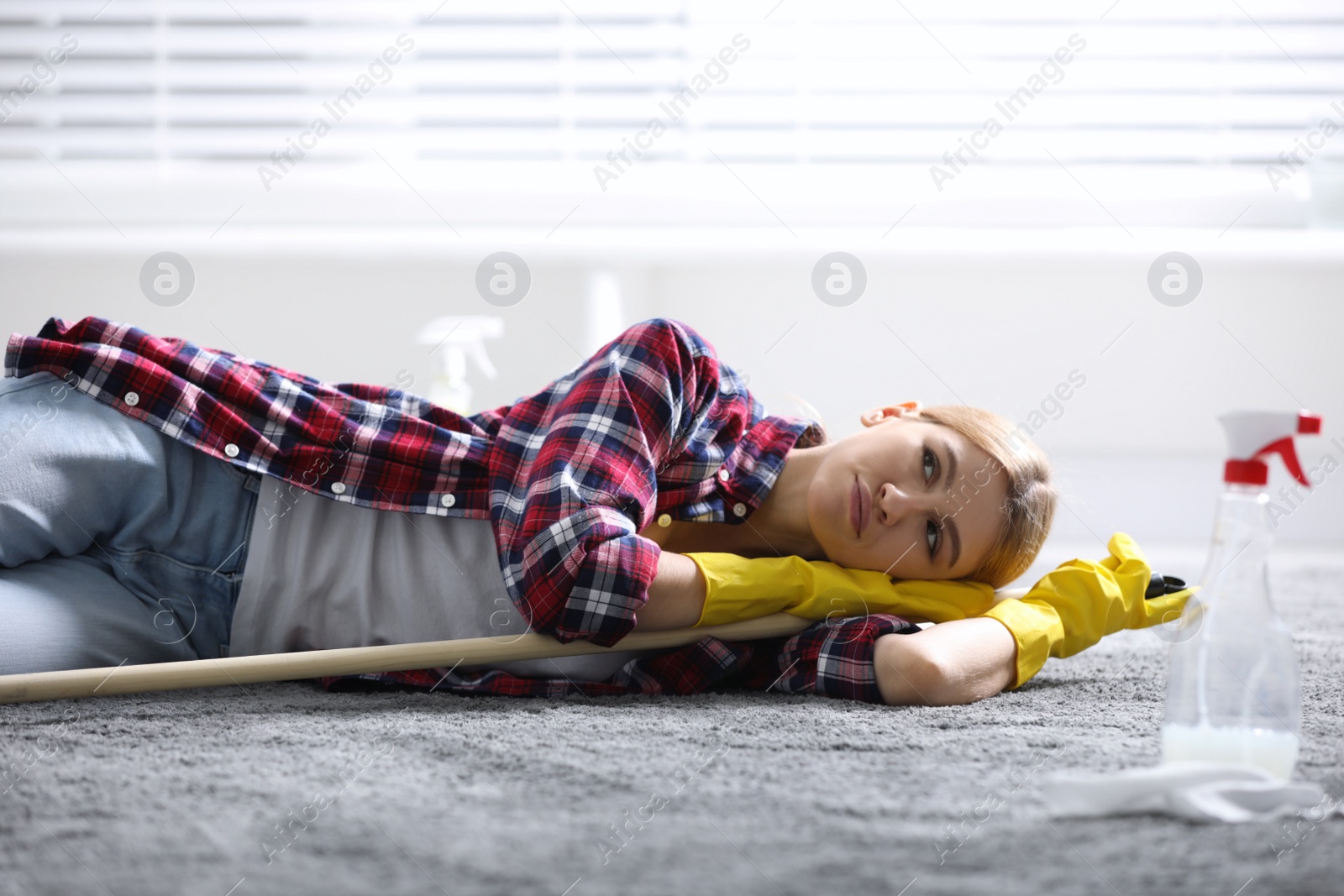 Photo of Lazy young woman with mop lying on floor at home. Cleaning and housework
