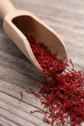 Photo of Aromatic saffron and scoop on wooden table, closeup