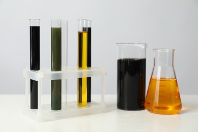 Photo of Laboratory glassware with different types of oil on white table