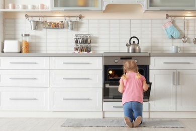 Photo of Little girl opening oven while baking in kitchen. Space for text