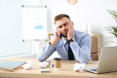 Photo of Lazy office employee talking on phone at workplace