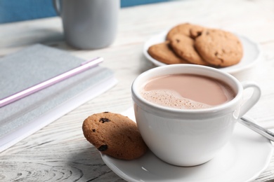 Photo of Cup with hot cocoa drink and cookie on table