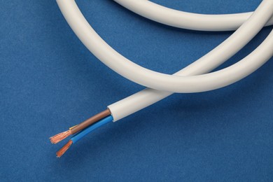 Photo of Electrical wires on blue background, closeup view