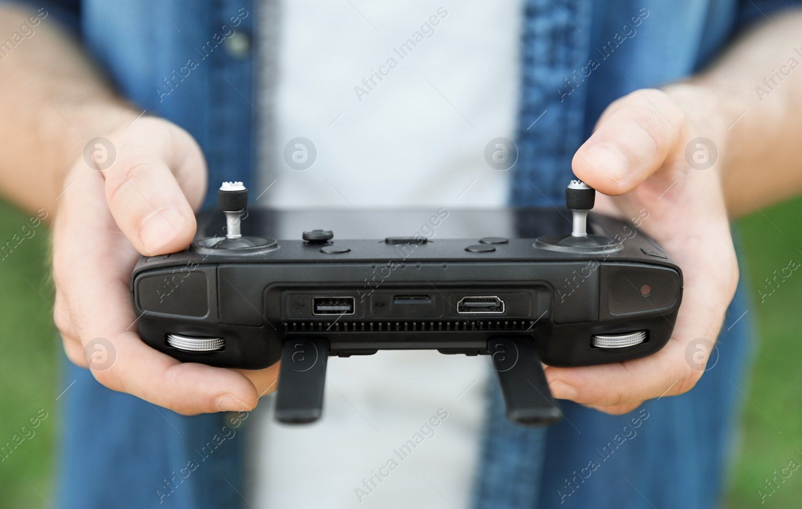 Photo of Man holding new modern drone controller outdoors, closeup of hands