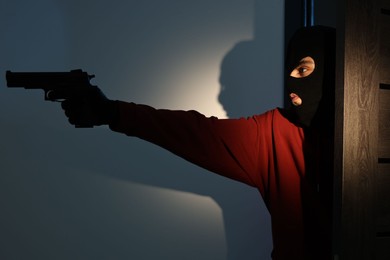 Photo of Thief with gun entering foreign house at night. Burglary