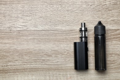 Photo of Electronic cigarette and liquid solution on wooden background, flat lay. Space for text