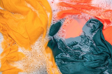 Colorful clothes in suds, top view. Hand washing laundry