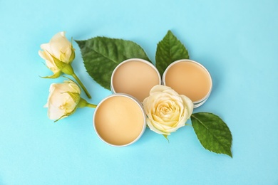 Photo of Hygienic lip balms and flowers on color background