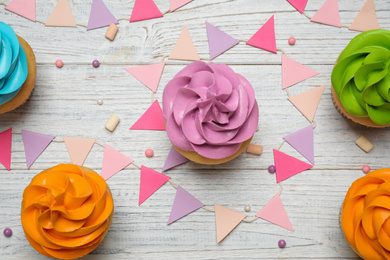 Photo of Colorful birthday cupcakes on white wooden table, flat lay