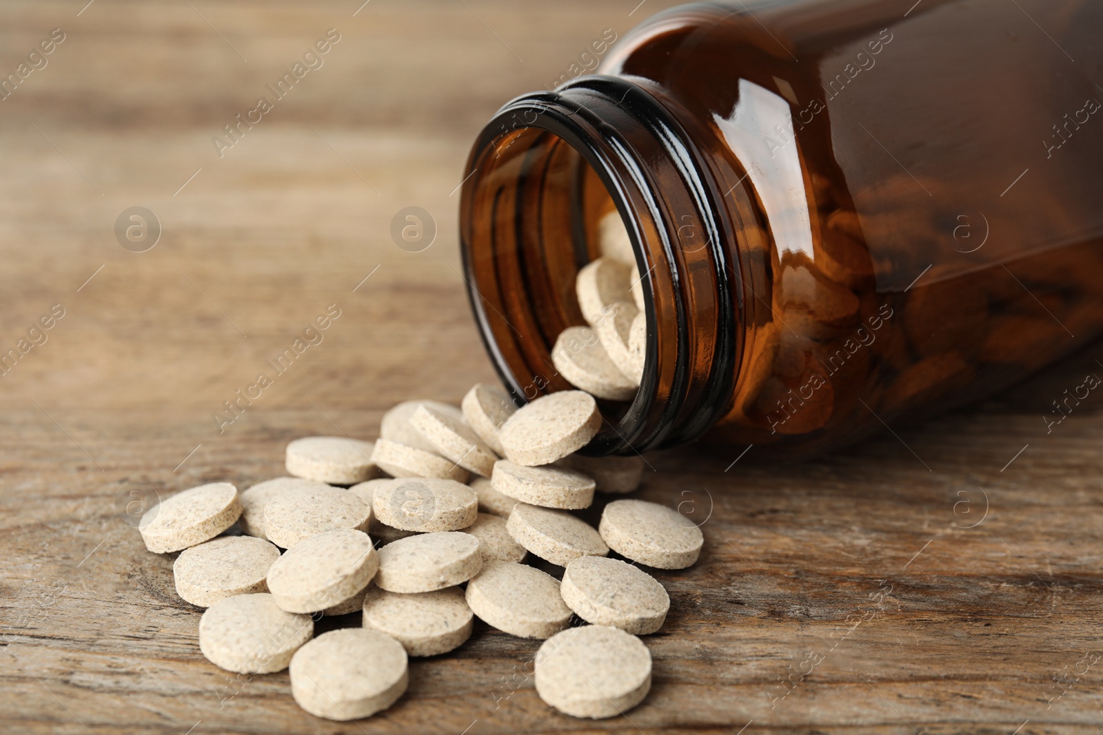Photo of Bottle with vitamin pills on wooden table, closeup