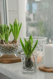 Photo of Beautiful bulbous plants and burning candles on windowsill indoors. Spring time