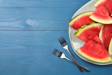 Plate with slices of juicy watermelon on blue wooden table, top view. Space for text