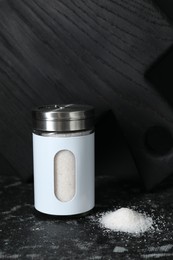 Photo of Stylish shaker with salt on dark table