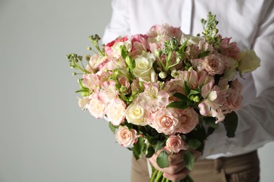Photo of Man with beautiful bouquet of flowers on grey background, closeup. Space for text