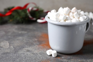 Photo of Cup of tasty hot drink with marshmallows on grey table, closeup. Space for text