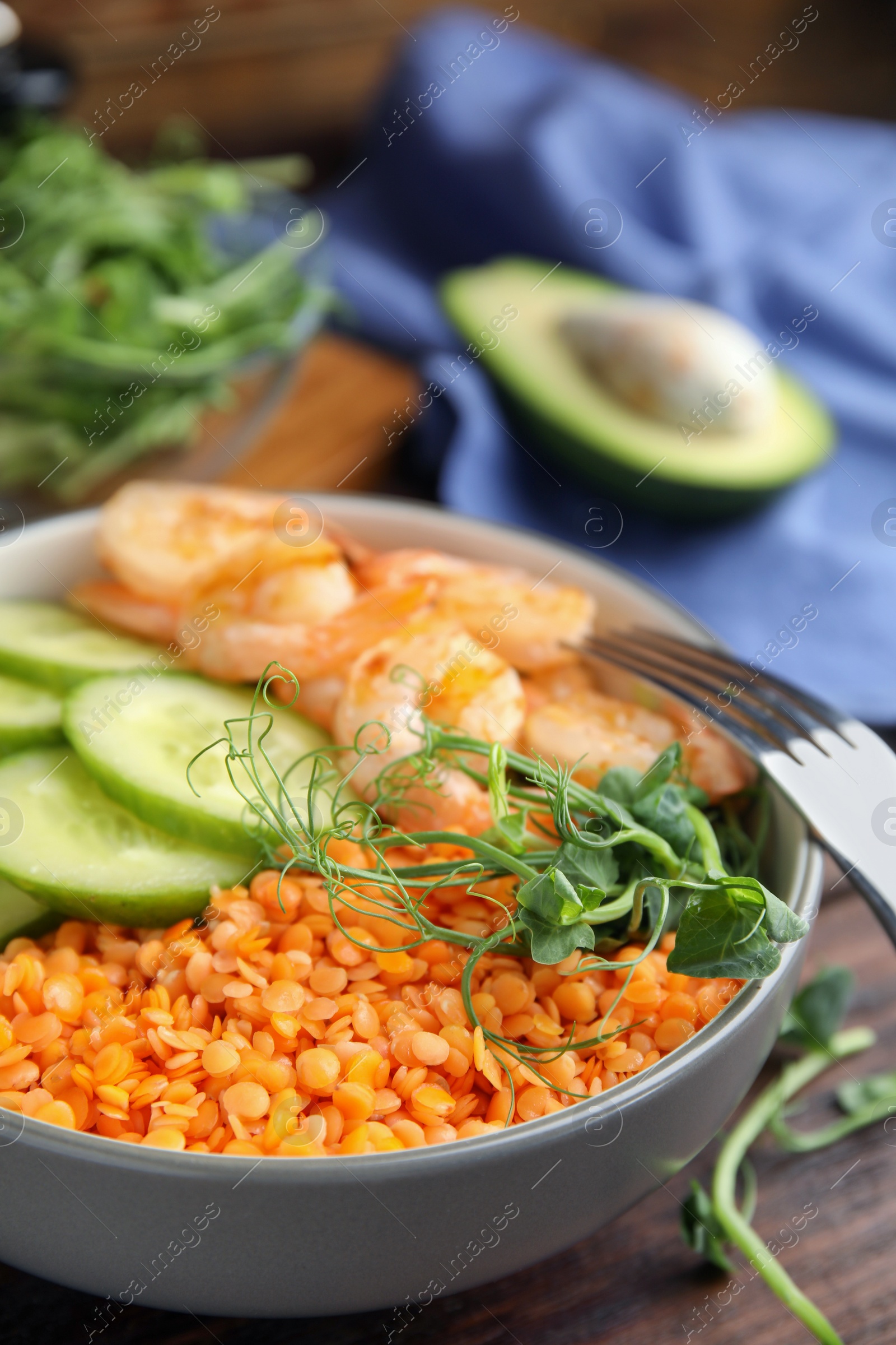 Photo of Delicious lentil bowl with shrimps and cucumber on wooden table, closeup