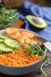 Delicious lentil bowl with shrimps and cucumber on wooden table, closeup