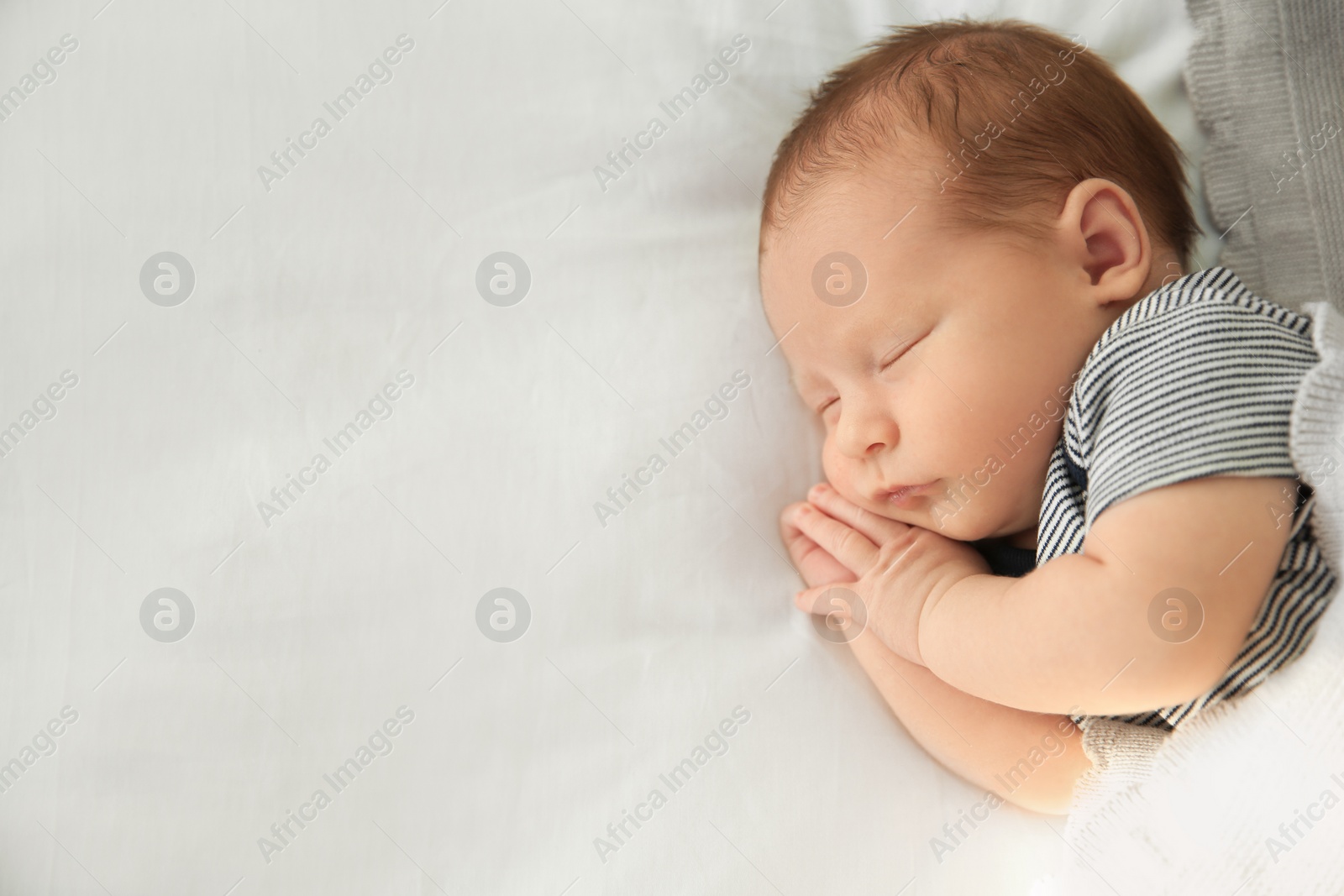 Photo of Adorable newborn baby peacefully sleeping on bed, top view with space for text