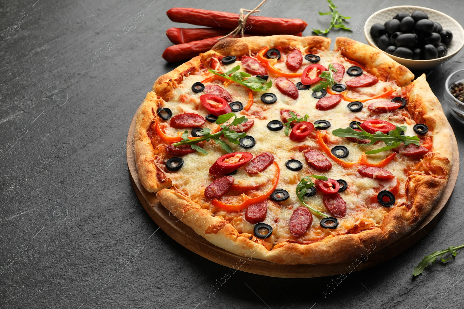 Photo of Tasty pizza and ingredients on black table