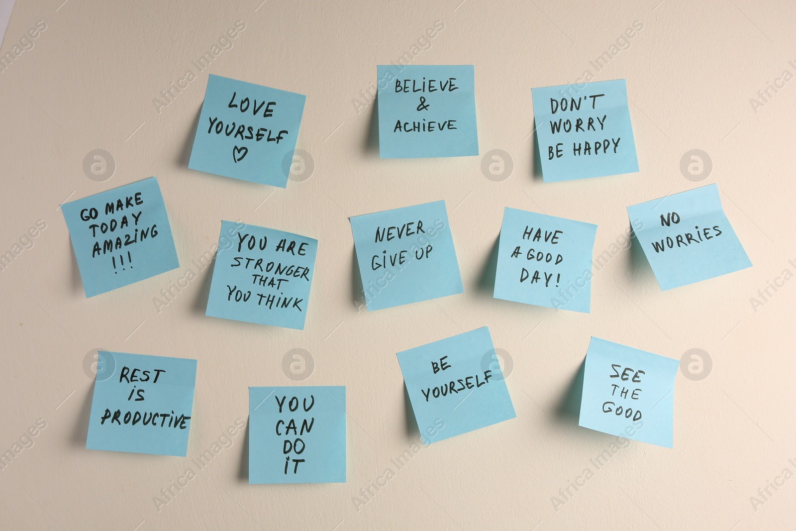 Photo of Paper notes with life-affirming phrases on white wall