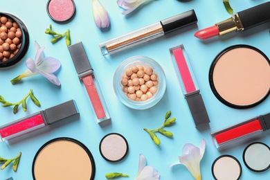 Makeup products and flowers on color background, flat lay