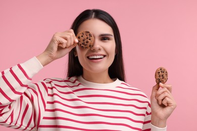 Young woman with chocolate chip cookies on pink background