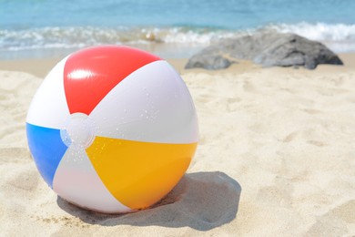 Wet colorful beach ball at seaside on sunny day, space for text