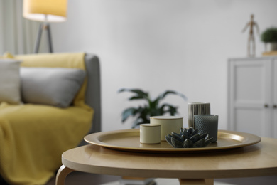 Photo of Wooden table with candles and tray in living room. Interior design