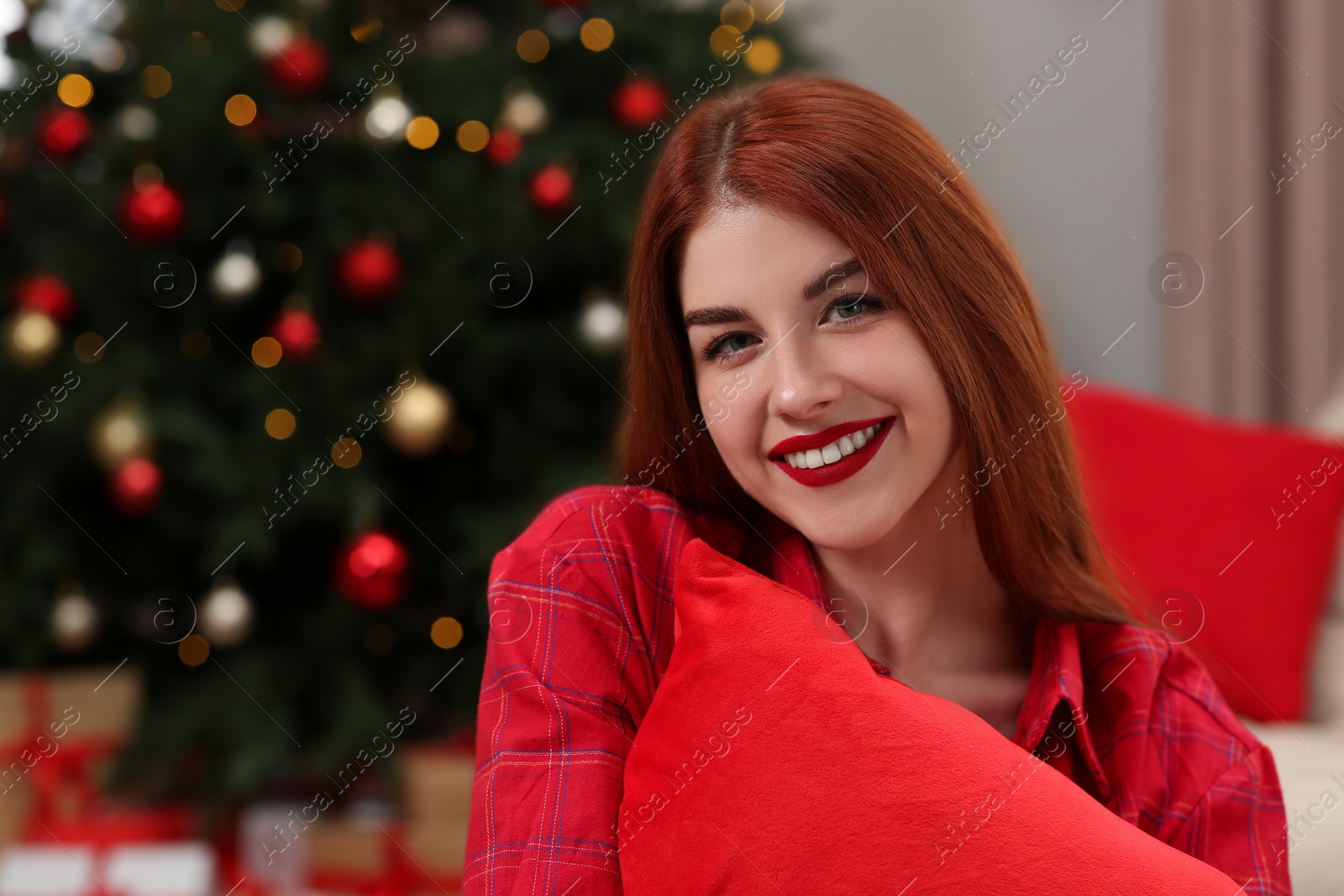 Photo of Beautiful young woman near Christmas tree indoors, space for text