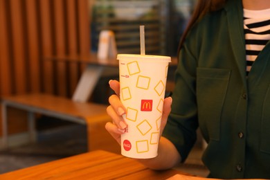 MYKOLAIV, UKRAINE - AUGUST 11, 2021: Woman with cold McDonald's drink in outdoor cafe, closeup